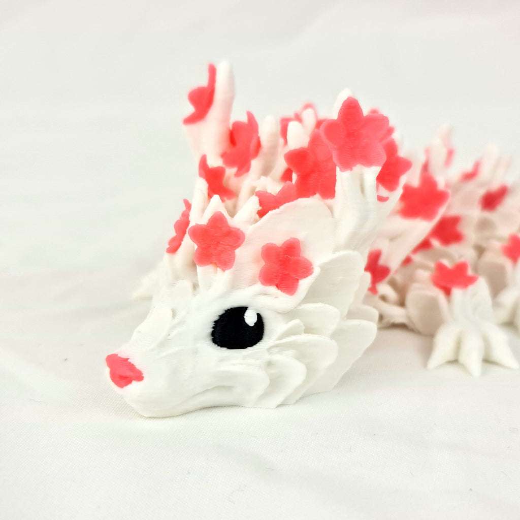 Close-up van het gedetailleerde gezicht van de roze 3D-geprinte cherryblossom baby draak met zwarte ogen.