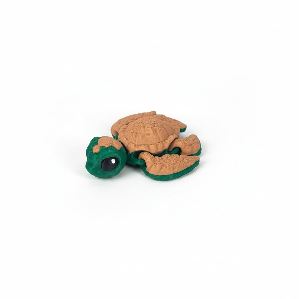 Handgemaakte 3D-geprinte flexibele schildpad met bruin lijf en groene schildsegmenten, gefotografeerd op een witte achtergrond.