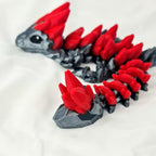 Detailfoto van de rode kristallen aan het uiteinde van de staart van de zwarte gemstone baby draak.