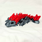 Overzicht van de gelede 3D-geprinte zwart-rode gemstone baby draak op een witte stof.