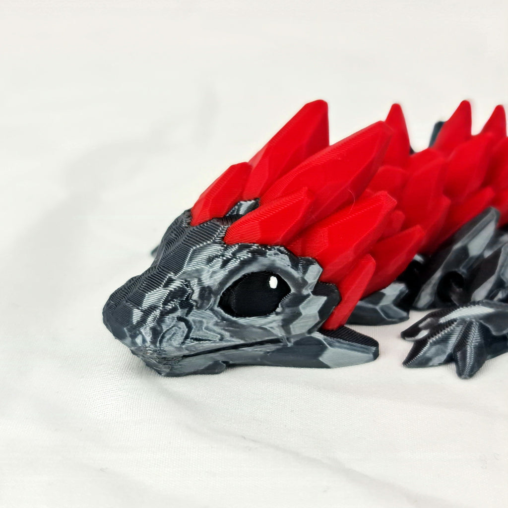 Vooraanzicht van de kop van de zwarte gemstone baby draak met opvallende rode kristallen.