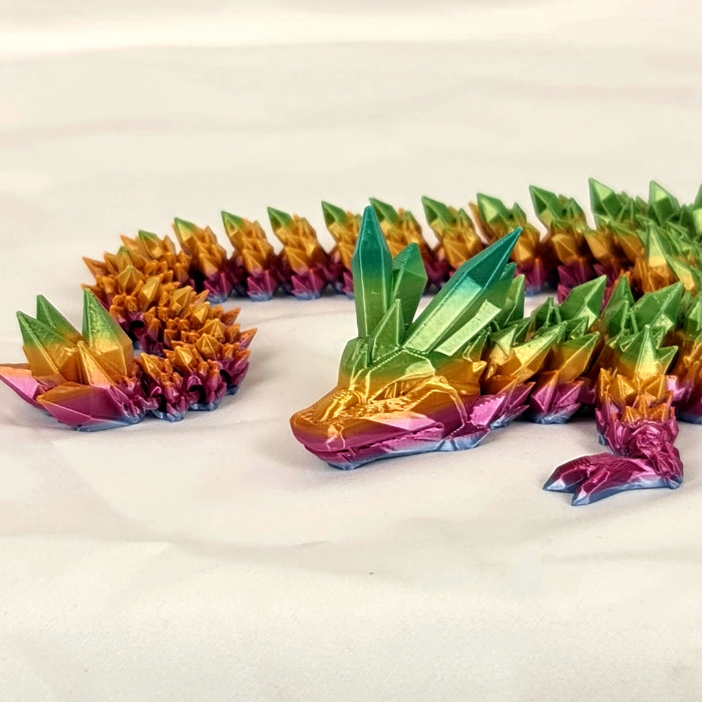 Schuin vooraanzicht van de flexibele meerkleurige kristaldraak op een neutrale ondergrond.