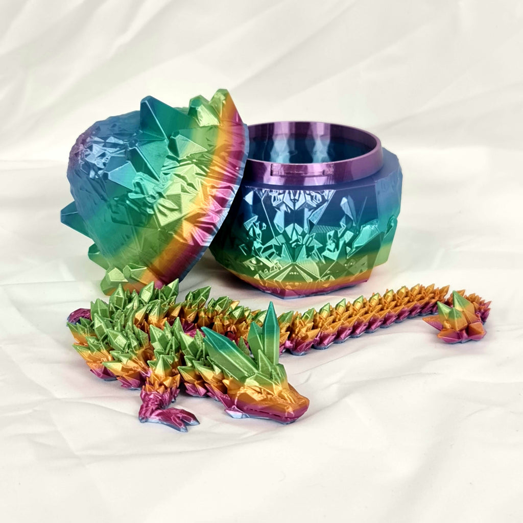 Overzicht van de regenboog kristaldraak liggend naast het geopende draakenei.
