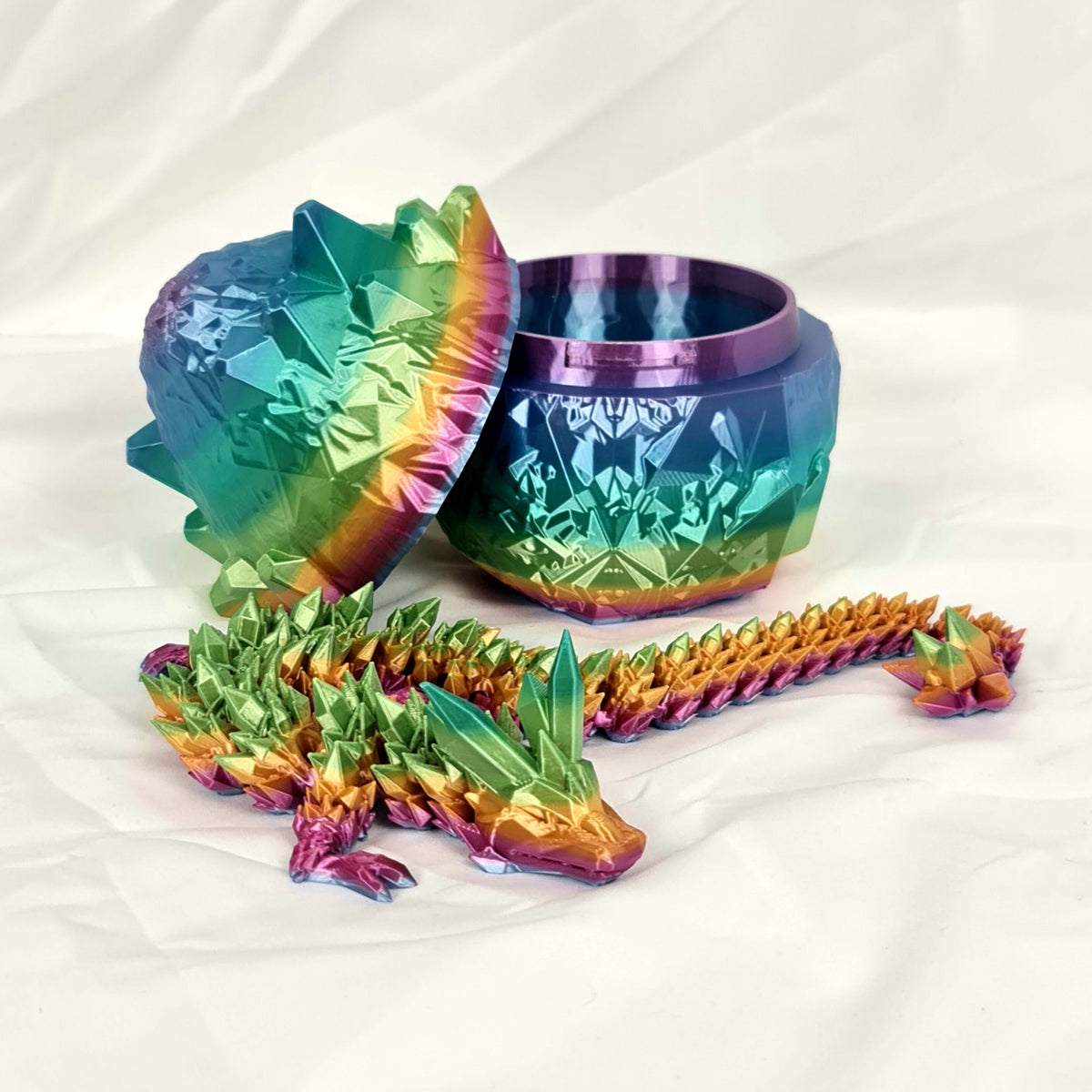 Overzicht van de regenboog kristaldraak liggend naast het geopende draakenei.