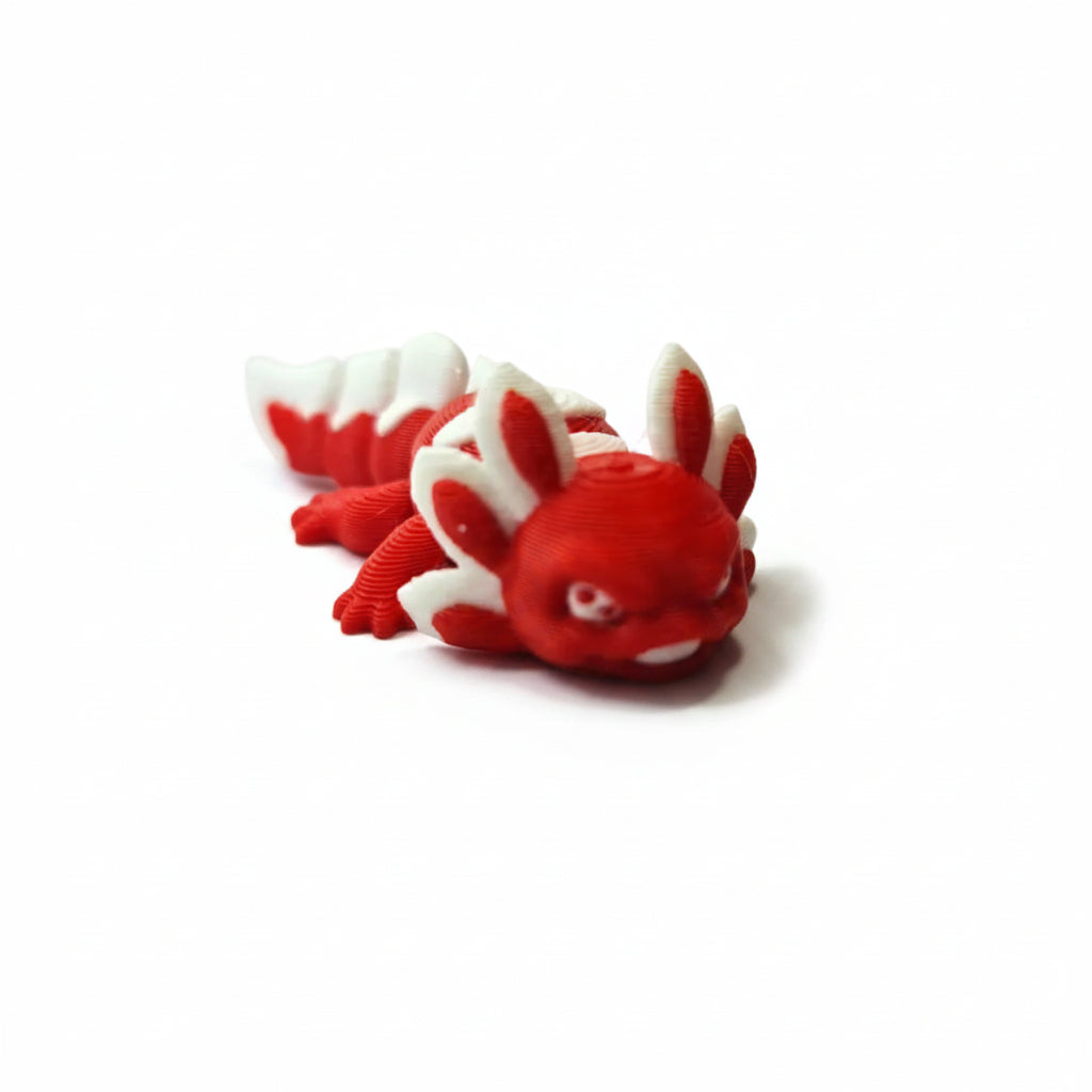 Handgemaakte 3D-geprinte flexibele mini axolotl Ruby in dieprood met witte accenten op een witte achtergrond, als uniek verzamelobject