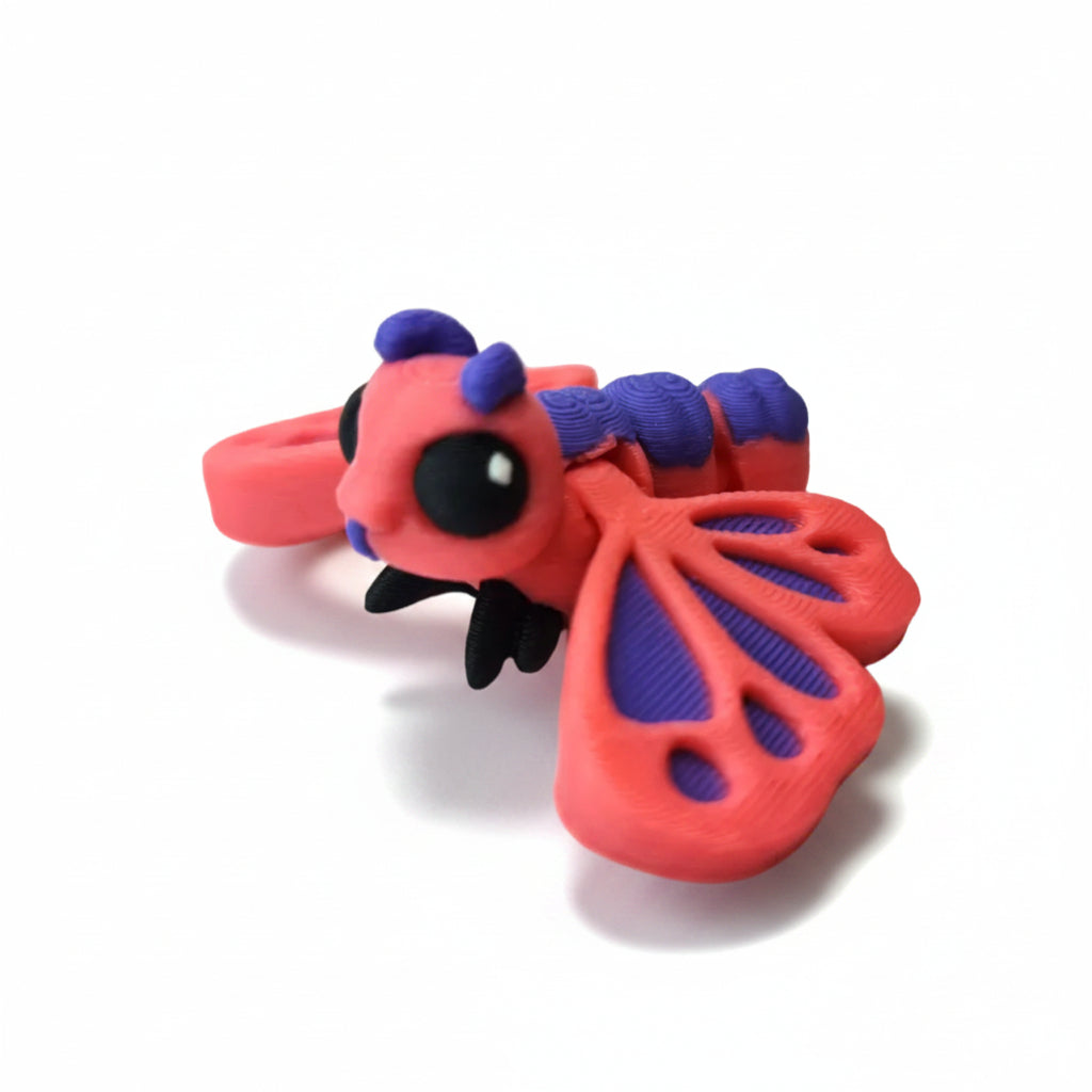 Handgemaakte 3D-geprinte flexibele mini vlinder in koraalroze en paars, met gedetailleerde vleugels, op een witte achtergrond.