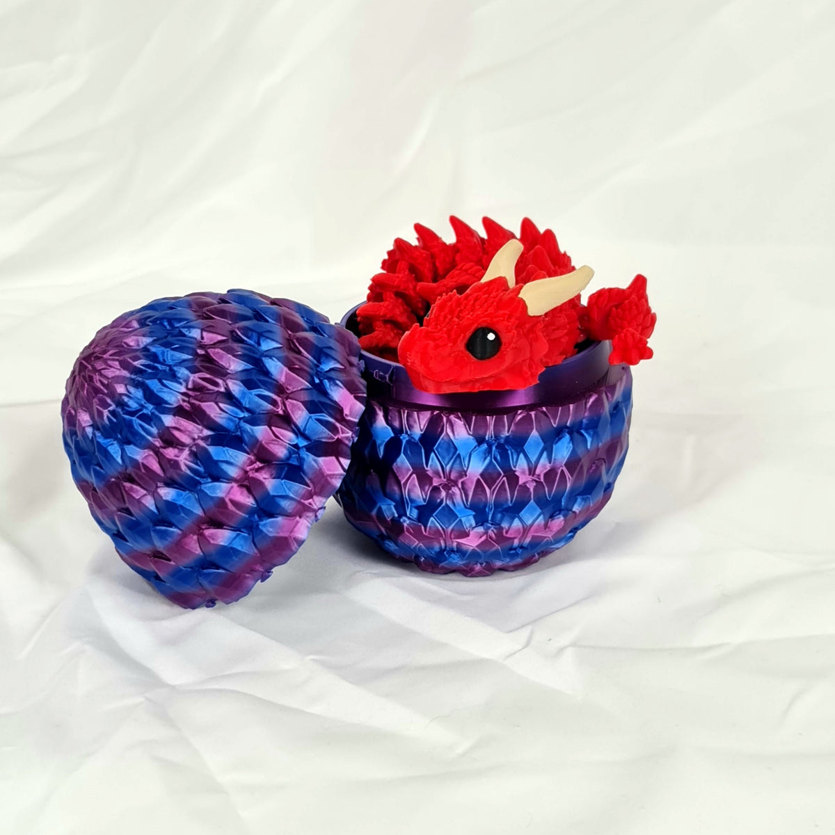 Schattige rode 3D-geprinte Ragnar draak die uit het geopende paars-blauwe draakenei glundert.