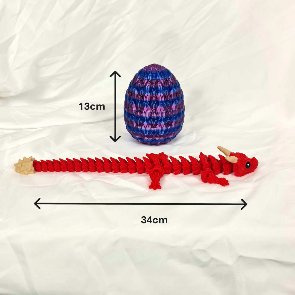 Overzicht van de gelede rode Ragnar draak en het paars-blauwe ei met maataanduidingen in centimeters.