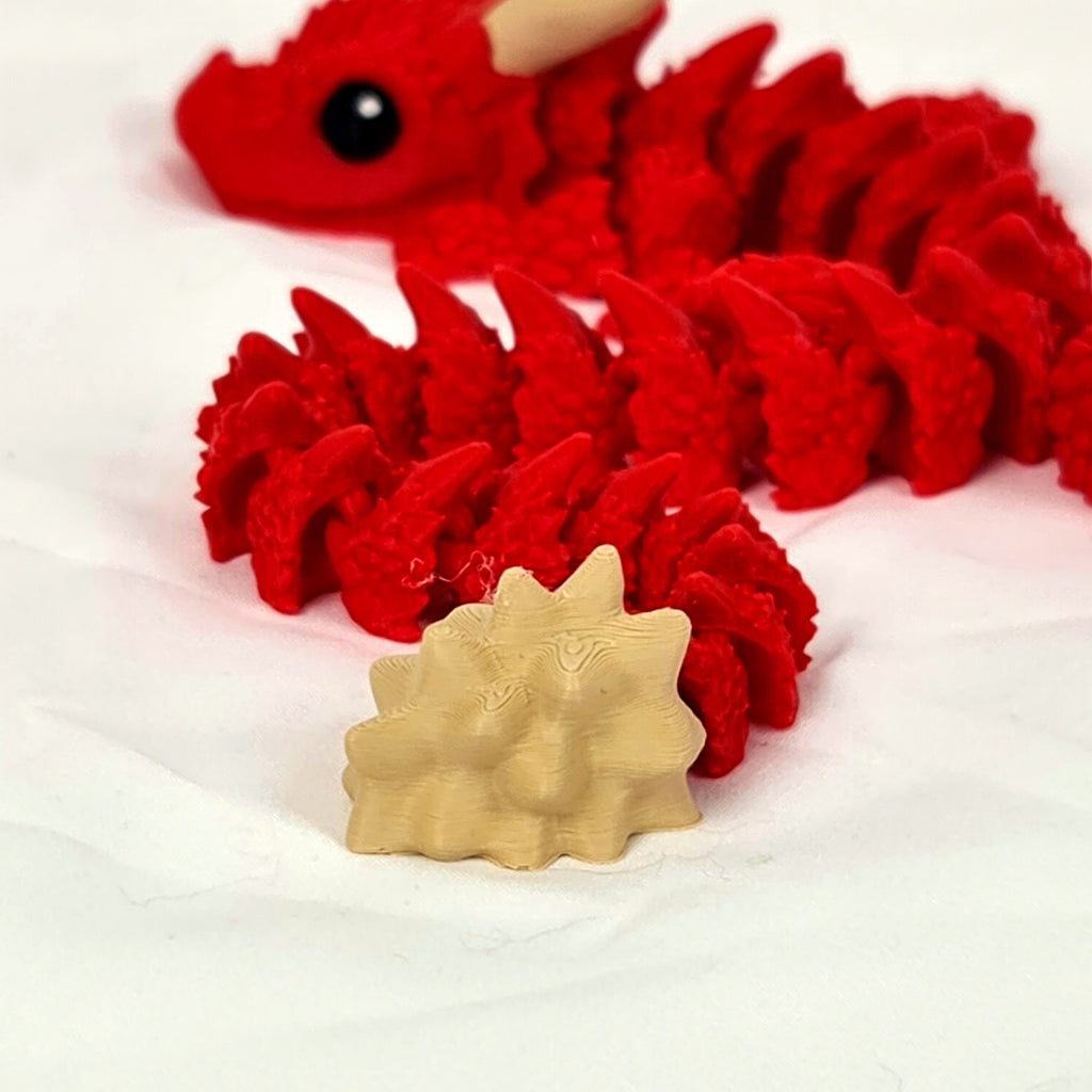 Detailfoto van de beige staartpunt en rode schubben van de gelede Ragnar draak.