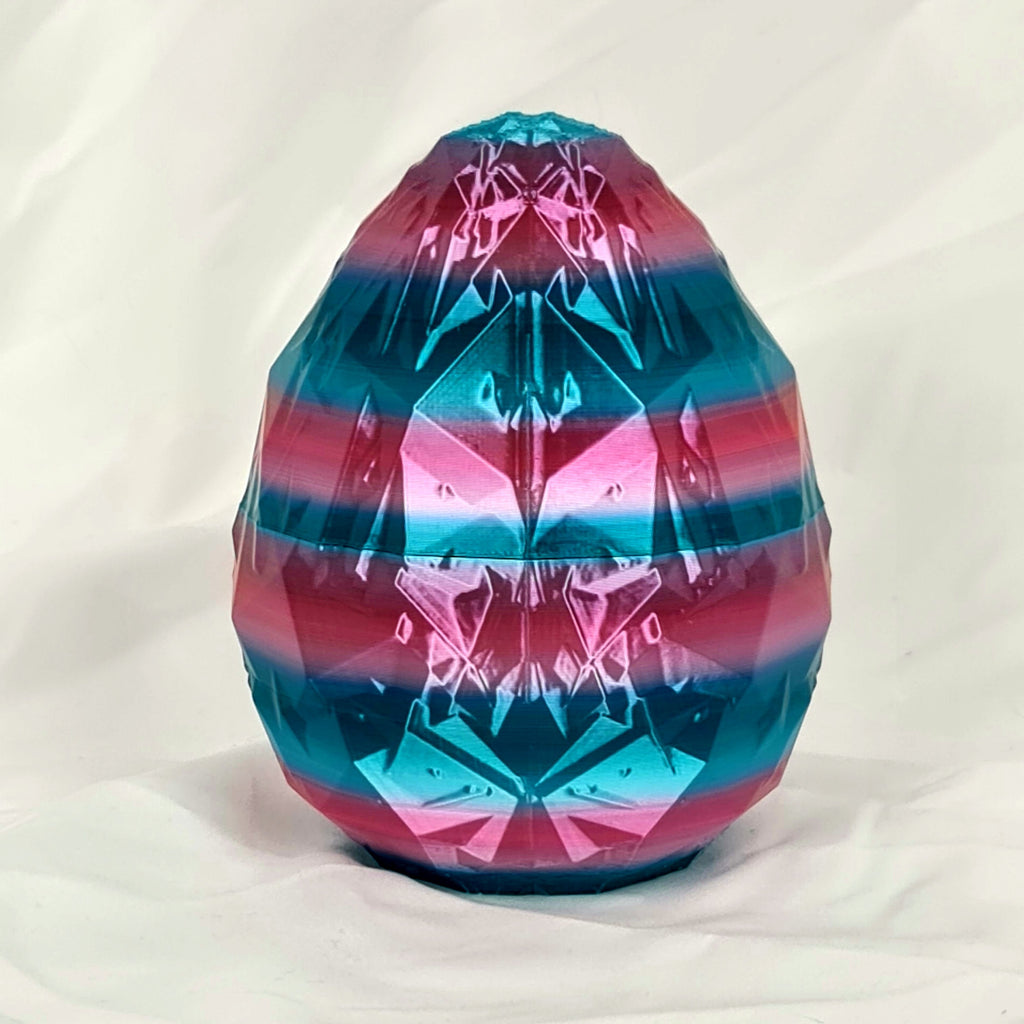 Gesloten 3D-geprint kristal-draakenei met glanzende metallic roze en blauwe strepen.