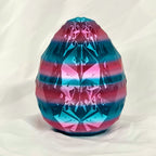 Gesloten 3D-geprint kristal-draakenei met glanzende metallic roze en blauwe strepen.