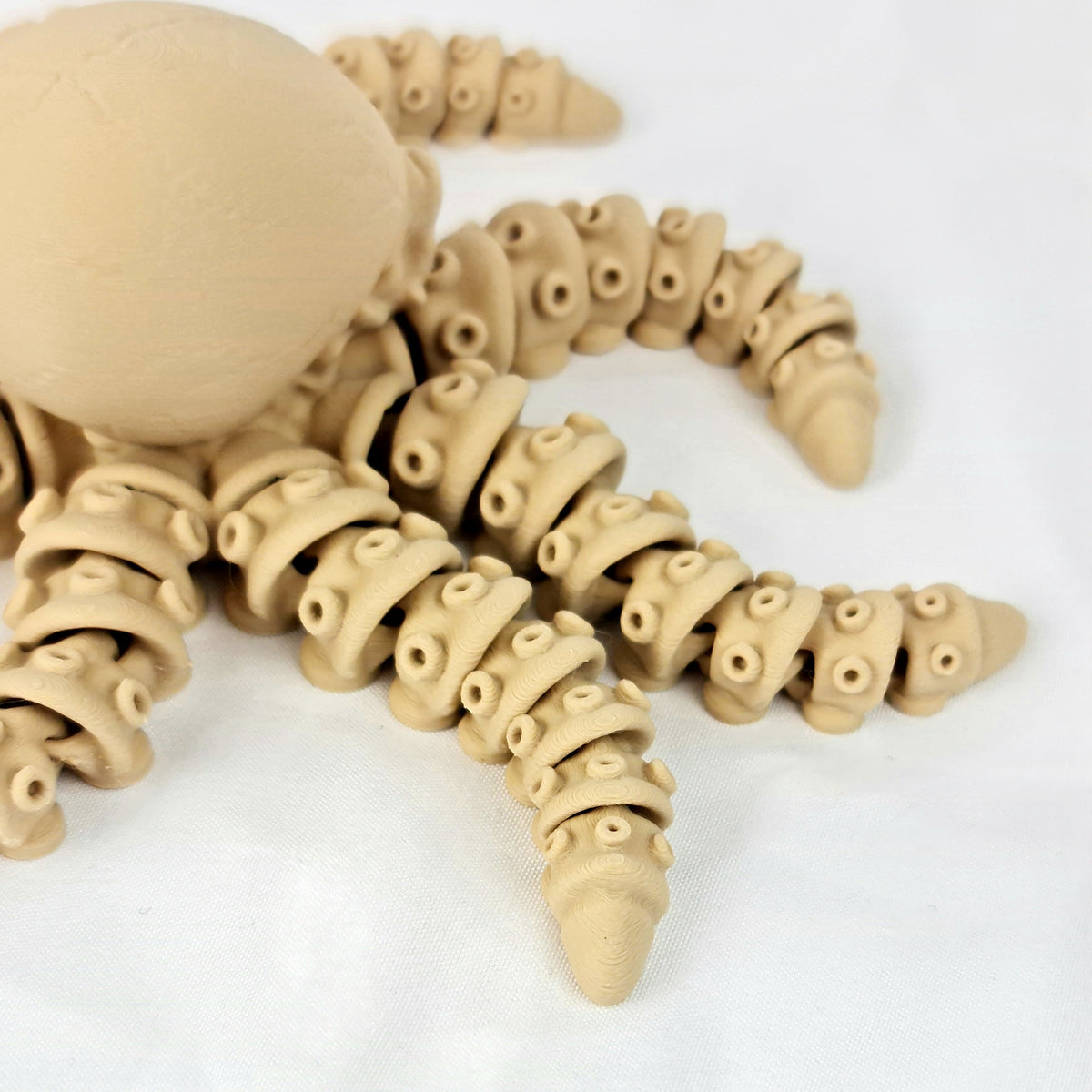 Zijaanzicht van de 3D-geprinte skelet octopus met bewegende armen op een schone witte achtergrond.