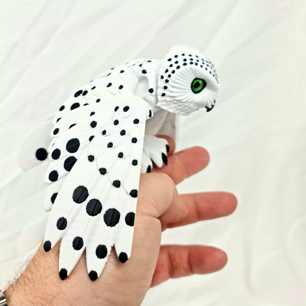 Close-up van de 3D-geprinte sneeuwuil met gevouwen vleugels in een hand