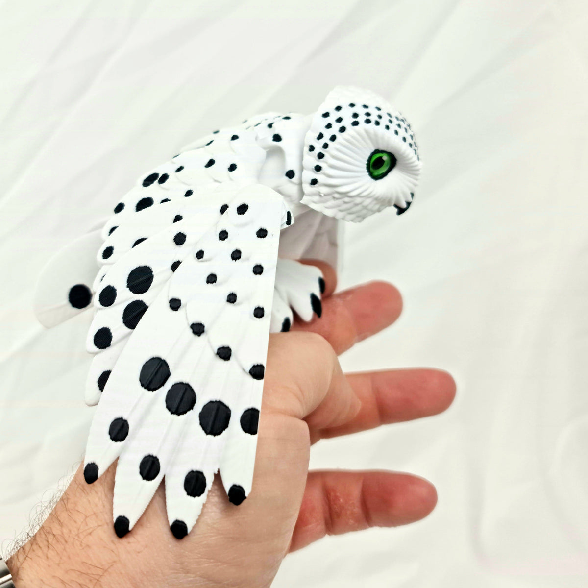 Close-up van de 3D-geprinte sneeuwuil met gevouwen vleugels in een hand