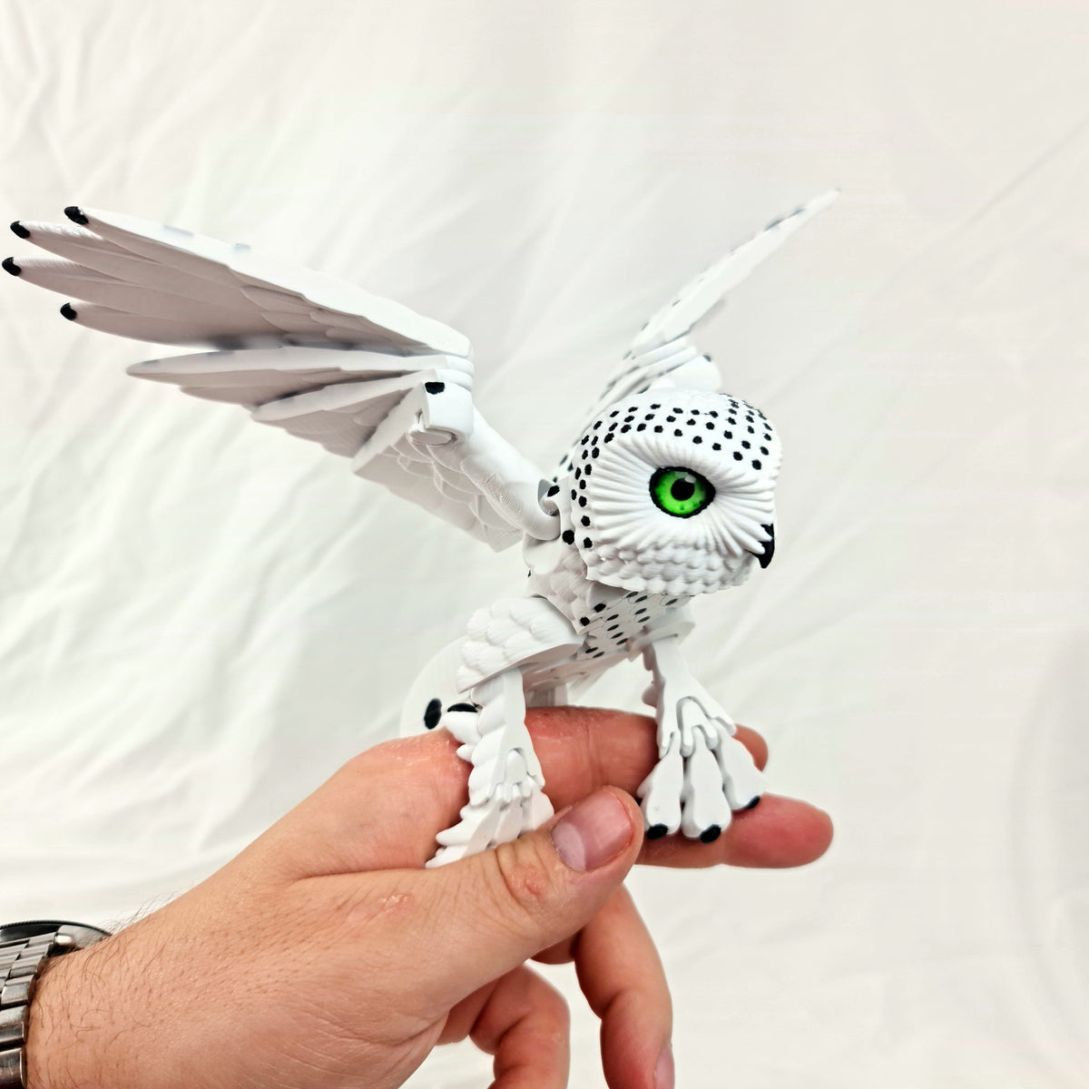 Beweegbare 3D-geprinte witte sneeuwuil vastgehouden in een hand voor formaatindicatie