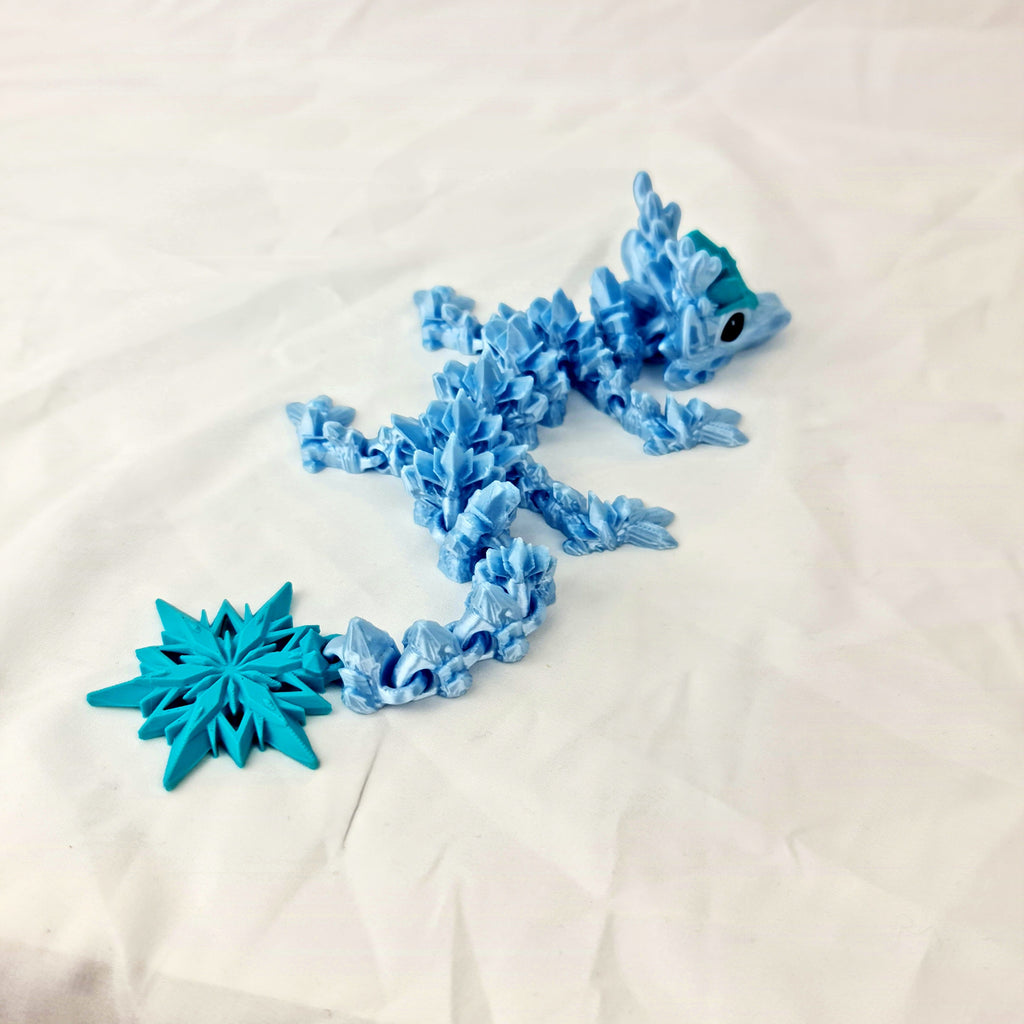Schuin bovenaanzicht van het buigzame lichaam van de lichtblauwe winter baby draak met sneeuwvlokstaart.