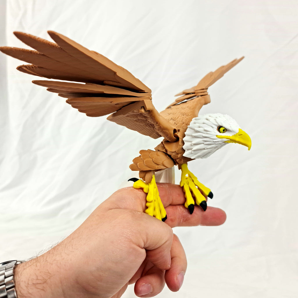 Beweegbare 3D-geprinte Amerikaanse zeearend met wijdgeopende bruine vleugels vastgehouden in een hand