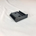 Close-up opname van de losse 3D-geprinte zwarte wandhouder en gereedschapssteun voor Makita LXT 18V apparatuur op witte stof
