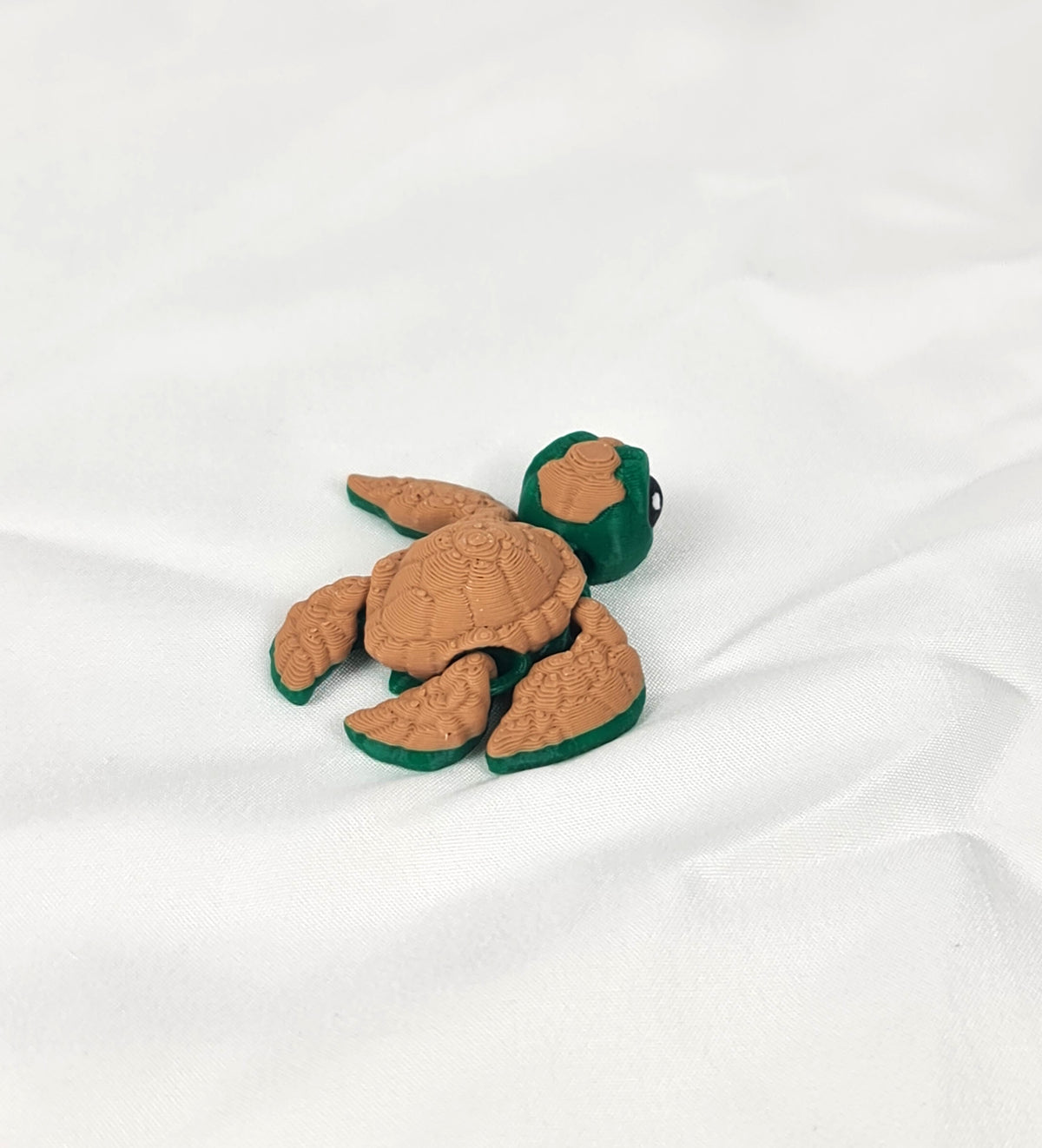 De 3D-geprinte flexibele schildpad gefotografeerd vanuit een andere hoek, duidelijk zichtbaar de articulatie van hoofd en flippers.