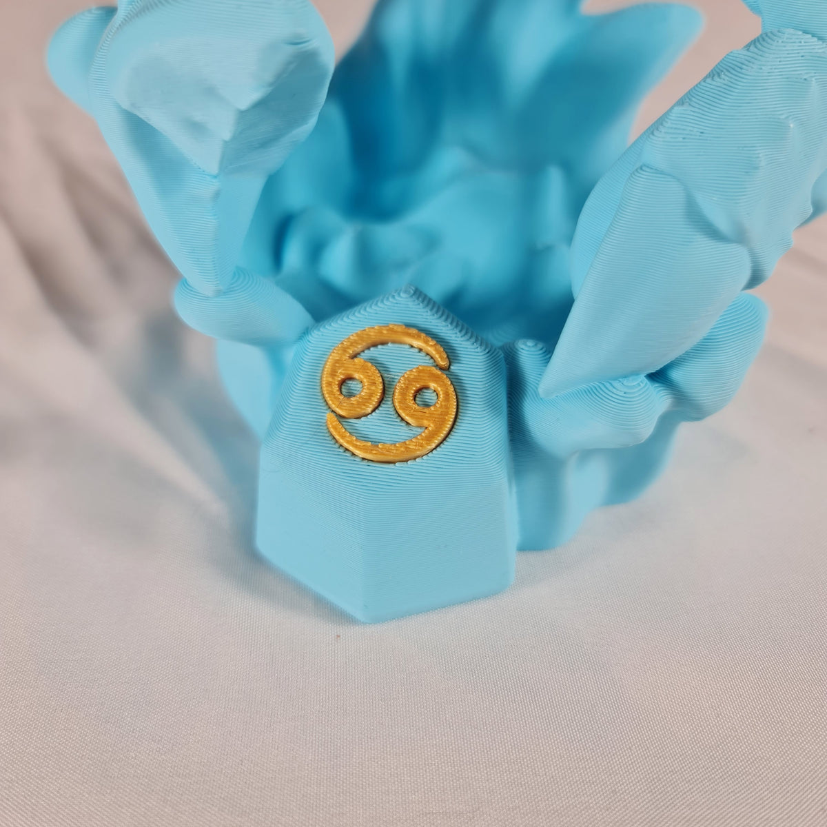 Close-up van het gouden astrologische Kreeft symbool op de sokkel van het handgemaakte 3D-geprinte beeld