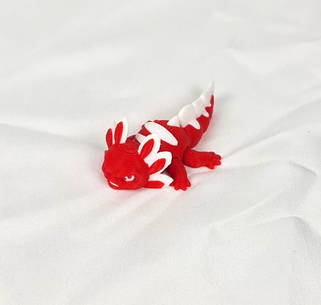Close-up opname van de gedetailleerde witte kieuwen en het flexibele rode lijf van de handgemaakte 3D-geprinte axolotl op witte stof