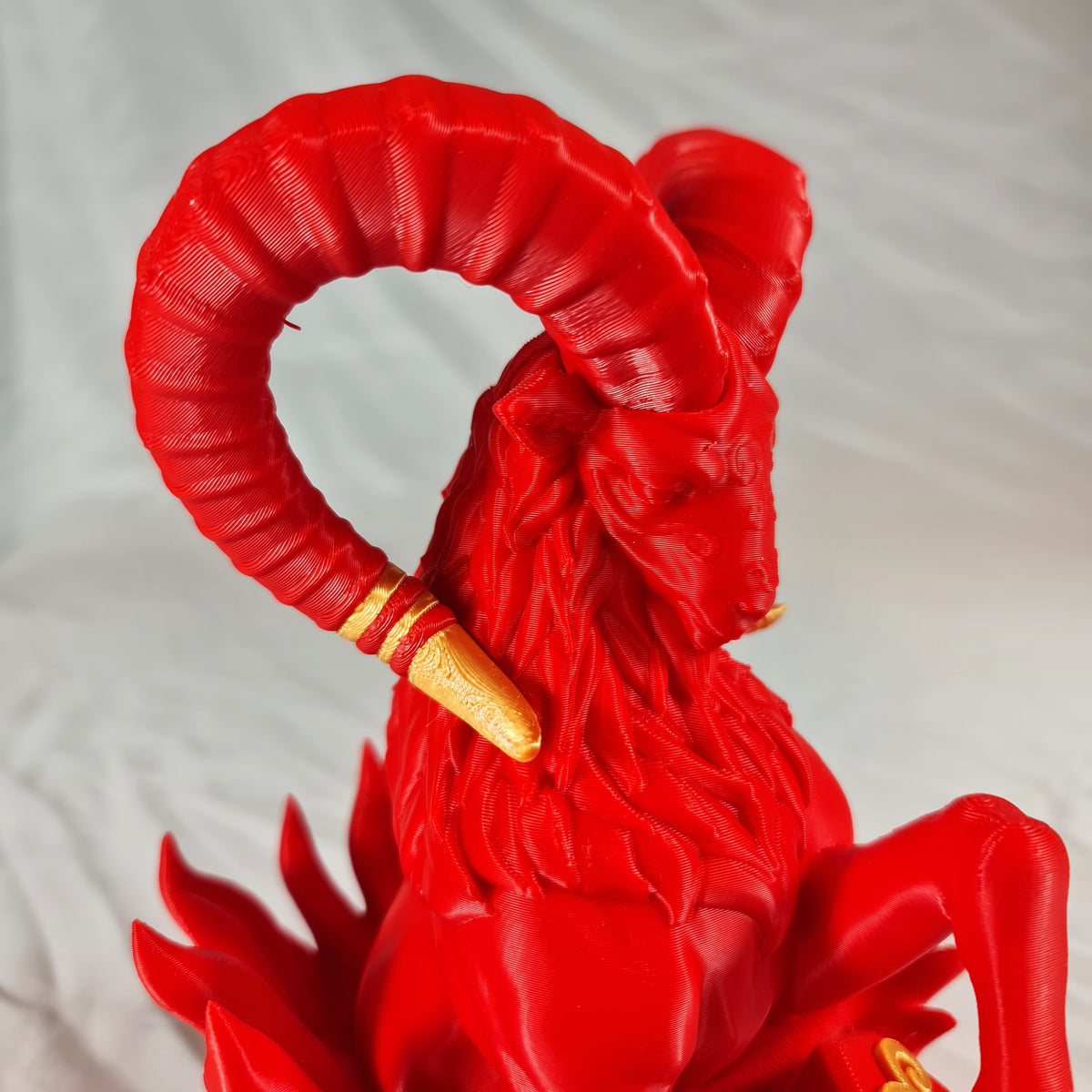Detailopname van de gedetailleerde kop en grote gekrulde hoorns met gouden accenten van het rode 3D-geprinte Ram sterrenbeeld beeld