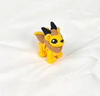 De gele en bruine 3D-geprinte flexibele mini manticore gefotografeerd vanuit een schuine hoek als decoratief kunstobject