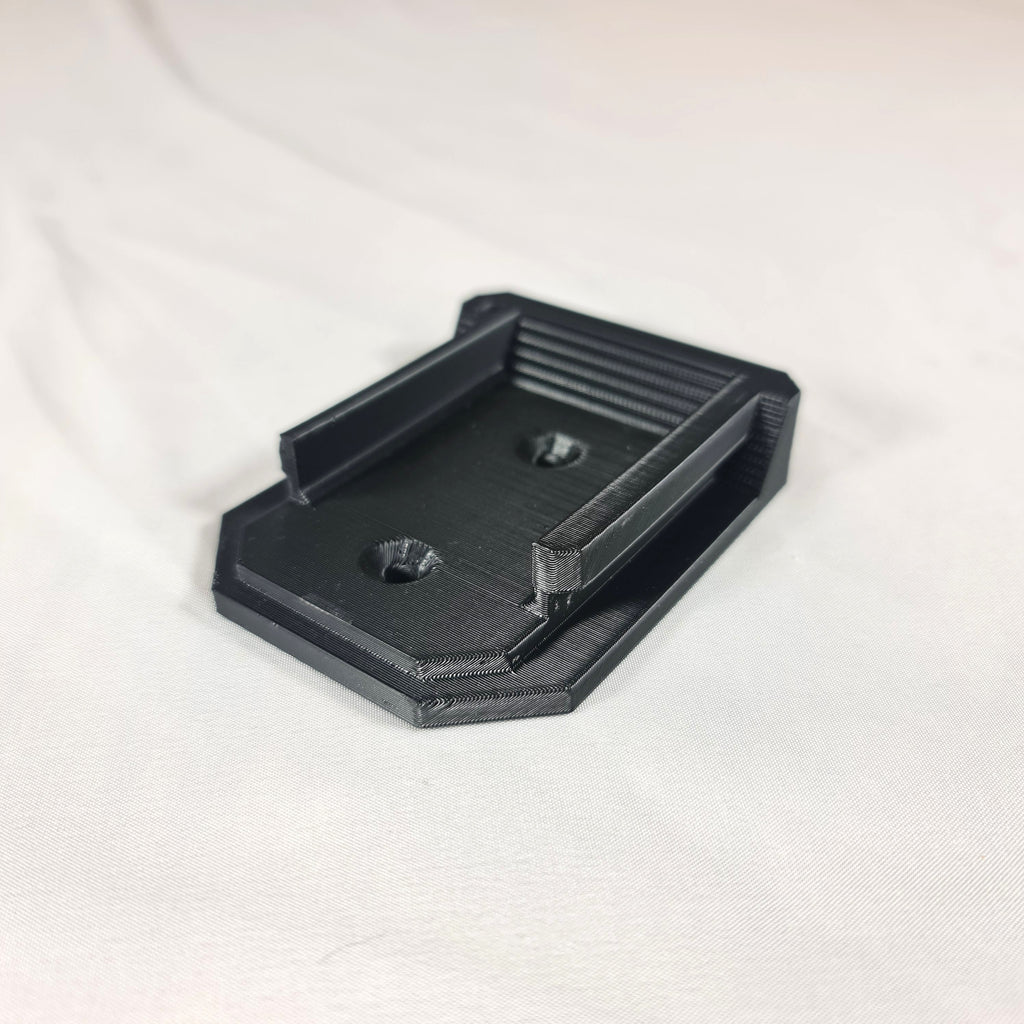 Schuine hoekweergave van de 3D-geprinte Makita LXT 18V gereedschapshouder inclusief de voorgevormde schroefgaten voor wandmontage