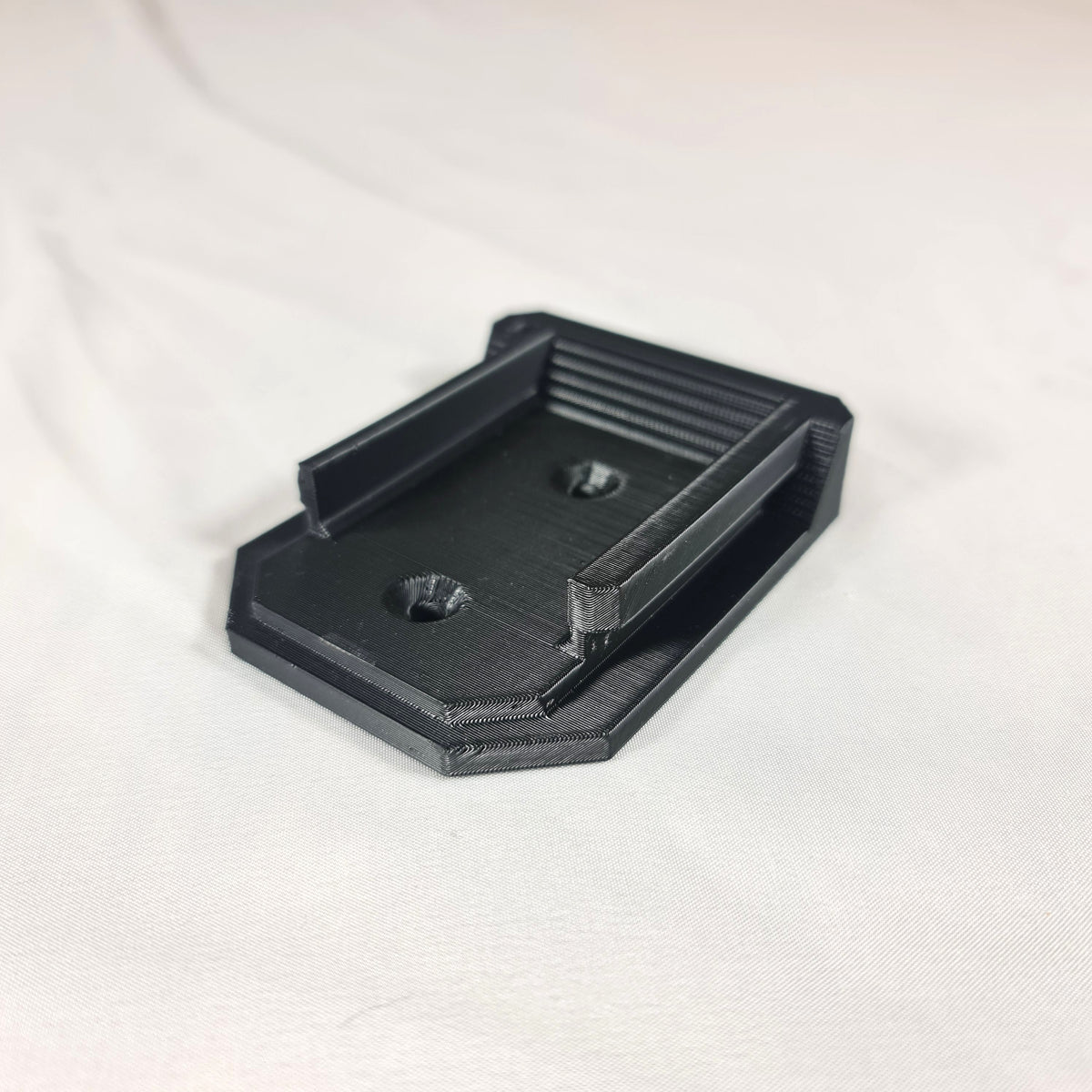 Schuine hoekweergave van de 3D-geprinte Makita LXT 18V gereedschapshouder inclusief de voorgevormde schroefgaten voor wandmontage