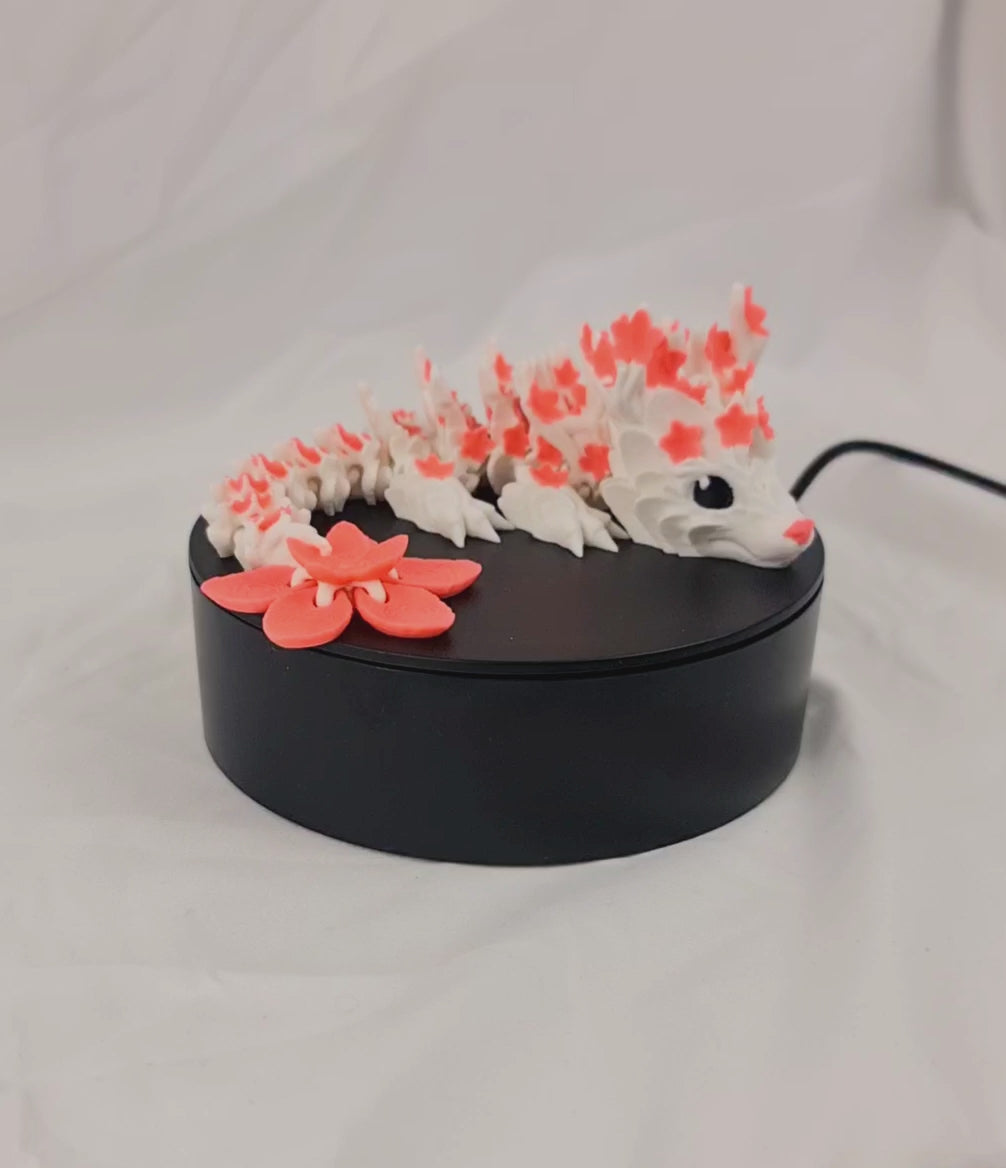 Video van de flexibele 3D-geprinte cherryblossom baby draak op een draaiend displayplatform.