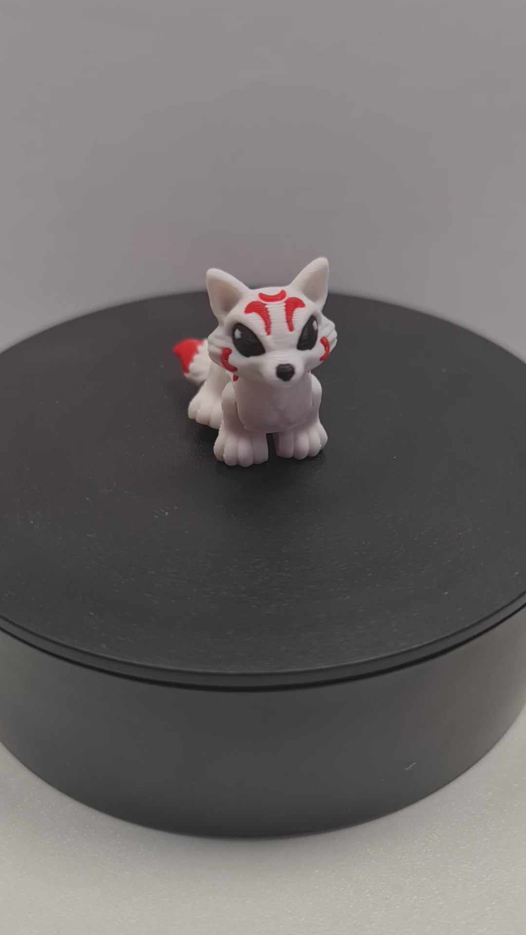 video still van de flexibele 3D-geprinte mini Kitsune die ronddraait op een zwarte draaitafel om de beweegbare gewrichten te tonen