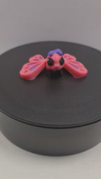 Video still van de flexibele 3D-geprinte mini vlinder die ronddraait op een zwarte draaitafel, om de volledige articulatie te tonen.