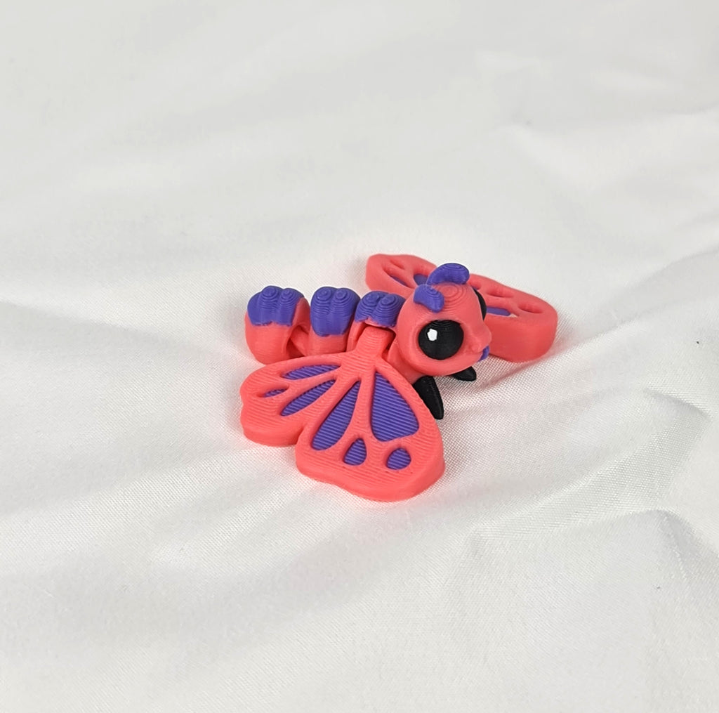 De 3D-geprinte flexibele vlinder gefotografeerd vanuit een schuine hoek, waarbij de schattige kraalogen goed zichtbaar zijn.