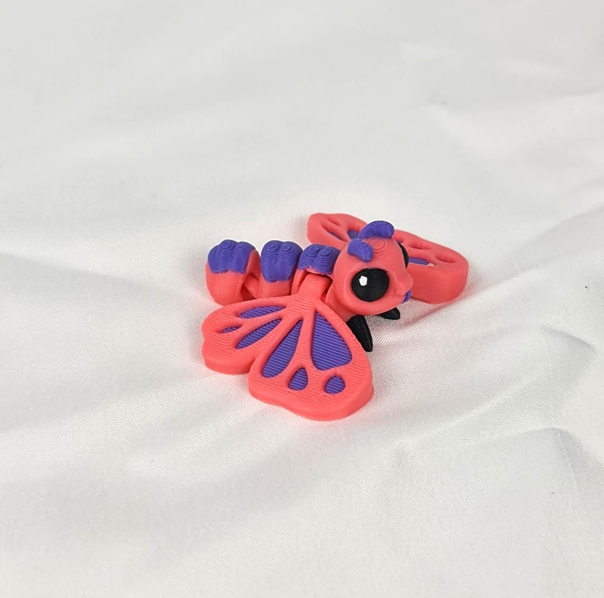 De 3D-geprinte flexibele vlinder gefotografeerd vanuit een schuine hoek, waarbij de schattige kraalogen goed zichtbaar zijn.