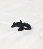De zwart-witte 3D-geprinte flexibele mini orca gefotografeerd vanuit een schuine hoek als decoratief kunstobject